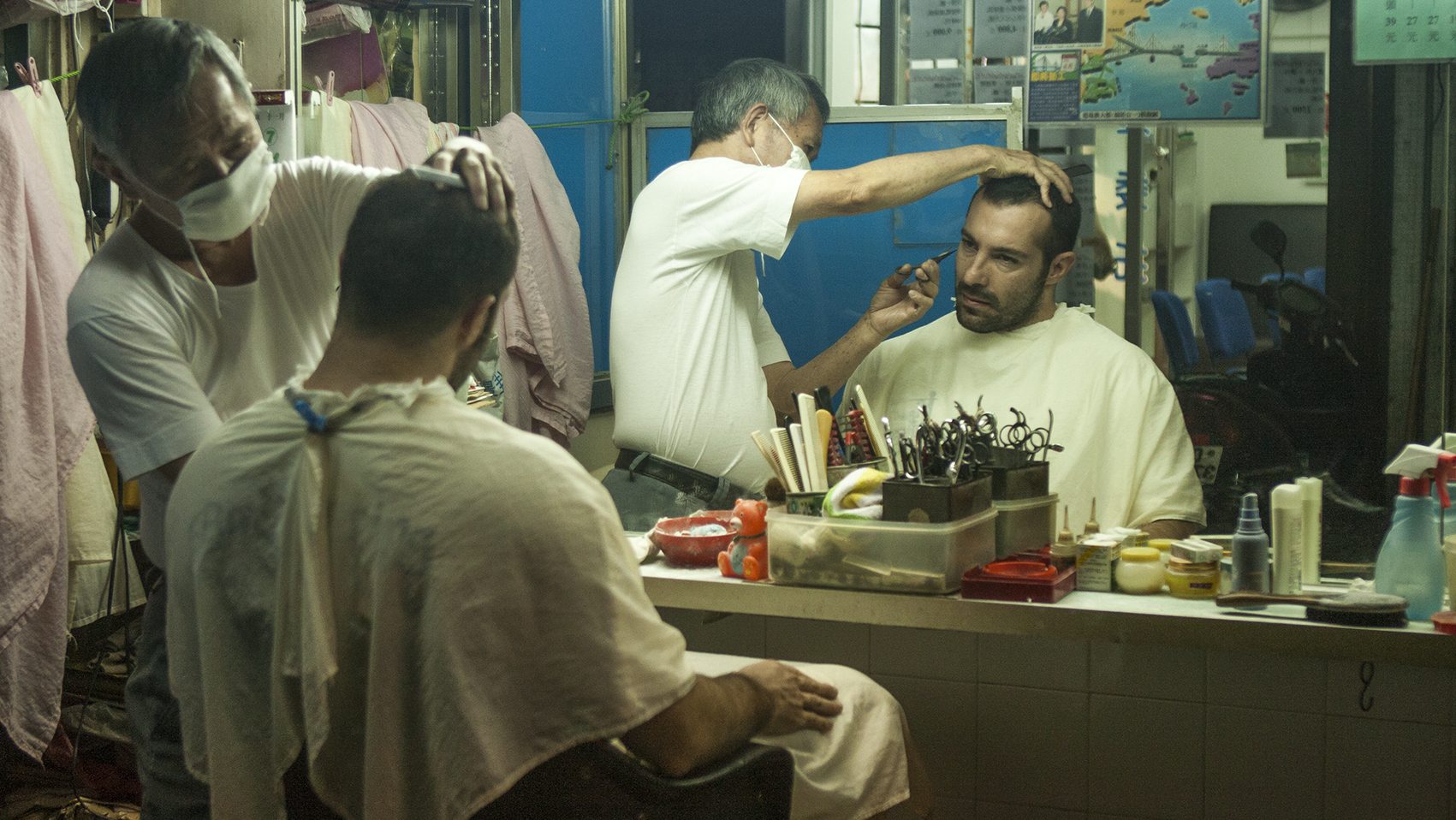 A person sitting on a street while a barber is trimming their hair, symbolising the importance of community interaction and cultural exchange.